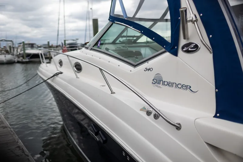 Slide: The Image of 2005 Sea Ray 340 Sundancer yacht docked at marina, featuring sleek design and blue canopy. - 2