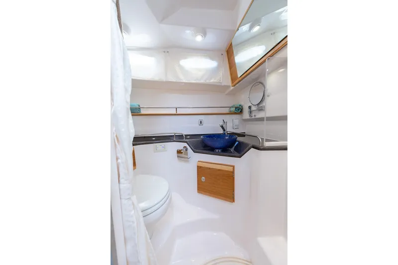 Slide: The Image of 2027 Cutwater C-32 CB boat bathroom with modern sink, mirror, and wooden accents. - 32