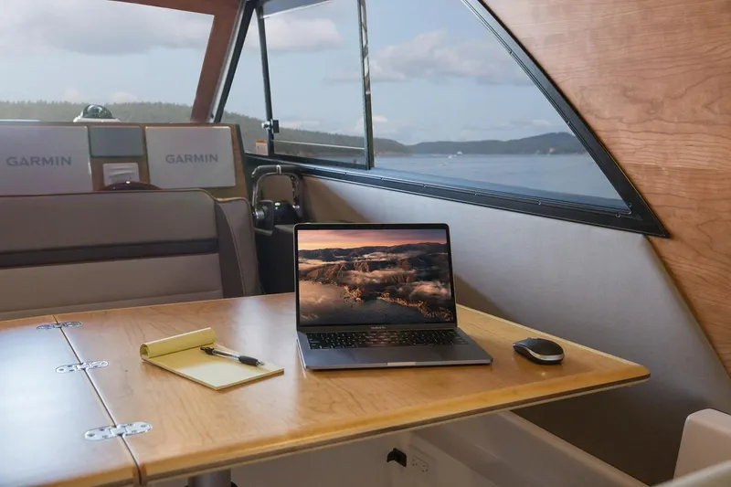 Slide: The Image of Interior of 2027 Cutwater C-32 CB boat with laptop, notepad, and scenic window view. - 19