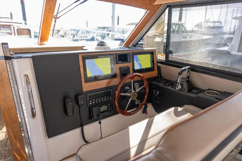 Slide: The Image of Helm of 2027 Cutwater C-32 CB boat with navigation screens and wooden steering wheel. - 15