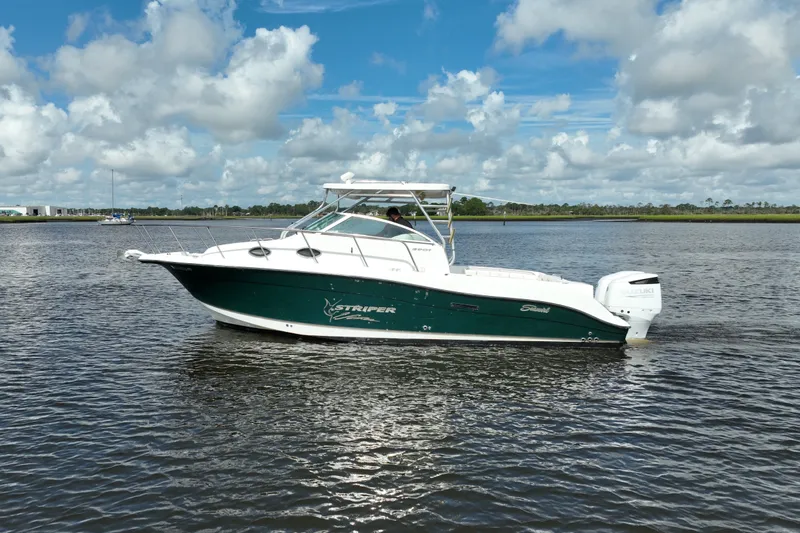 Slide: The Image of 2004 Seaswirl Striper 2901 Walkaround O/B boat on calm water under blue sky. - 13