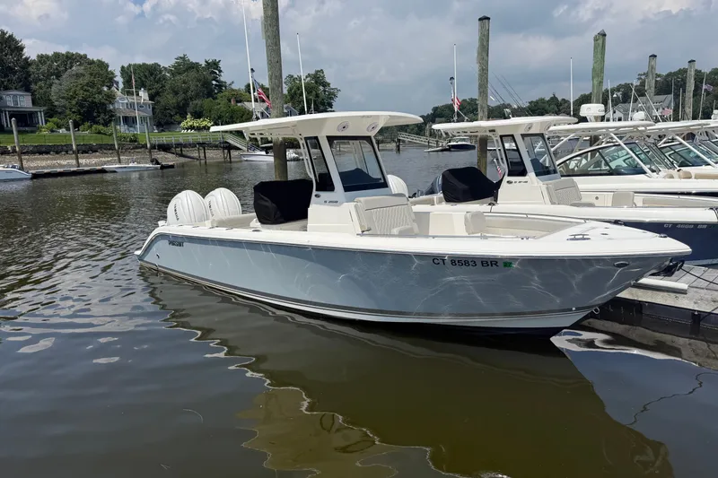 The Image of 2026 Pursuit S 268 Sport boat docked in a marina under a cloudy sky. - 0