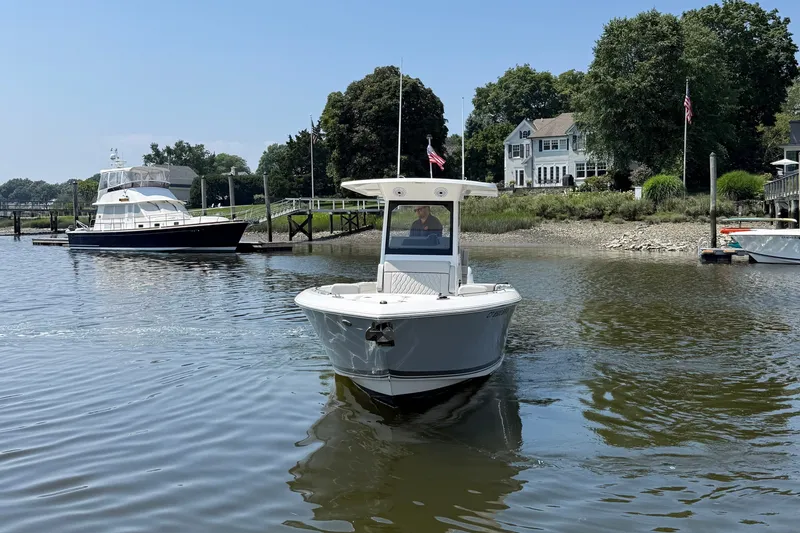 Slide: The Image of A 2026 Pursuit S 268 Sport boat navigates a calm river, surrounded by trees and houses. - 16
