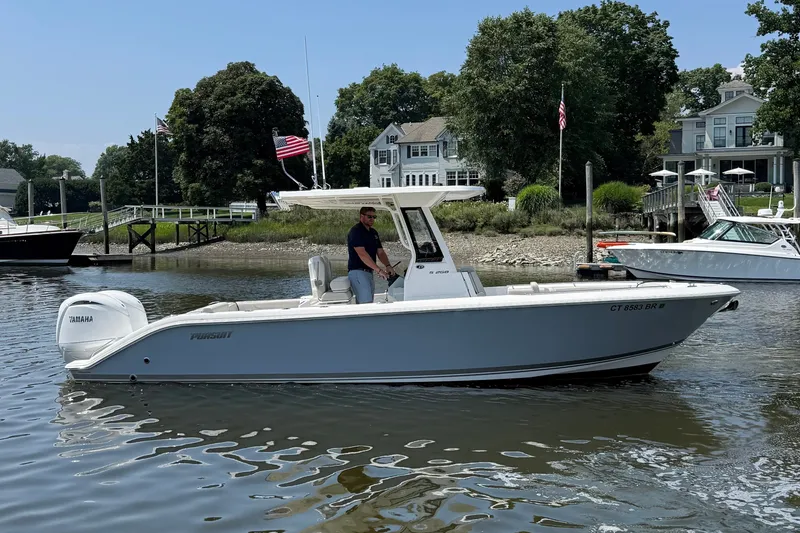 Slide: The Image of A modern Pursuit S 268 Sport boat on calm water, with a man at the helm. - 17
