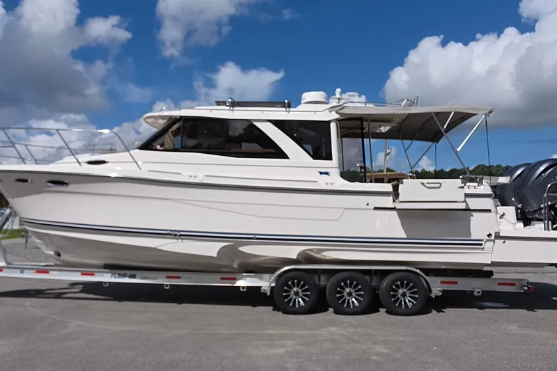 Slide: The Image of 2027 Cutwater C-32 Coupe boat on trailer under blue sky with clouds. - 31