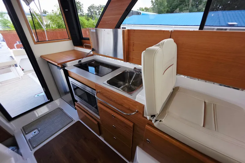 Slide: The Image of Interior of 2027 Cutwater C-32 Coupe featuring a compact kitchen with stove and sink. - 11