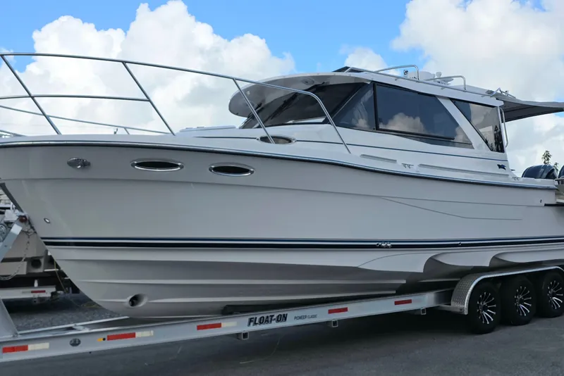 The Image of 2027 Cutwater C-32 Coupe boat on trailer under blue sky. - 1