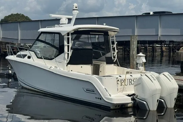 Slide: The Image of 2023 Boston Whaler 325 Conquest boat docked, featuring twin Mercury engines. - 62