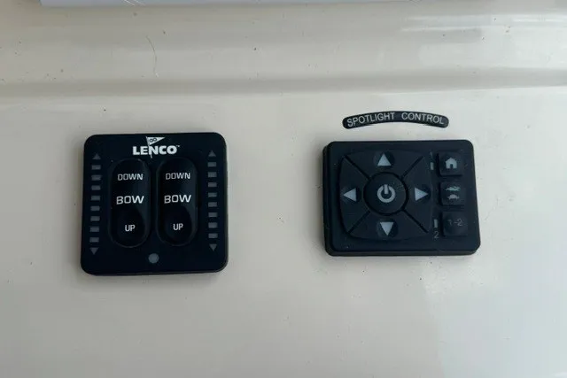Slide: The Image of Control panels on a 2023 Boston Whaler 325 Conquest boat, featuring Lenco and spotlight controls. - 56