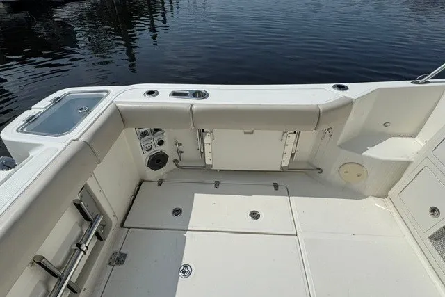 Slide: The Image of 2023 Boston Whaler 325 Conquest boat deck with seating and storage, docked by calm water. - 25