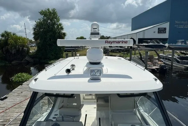 Slide: The Image of 2023 Boston Whaler 325 Conquest boat with Raymarine radar, docked near a marina. - 59