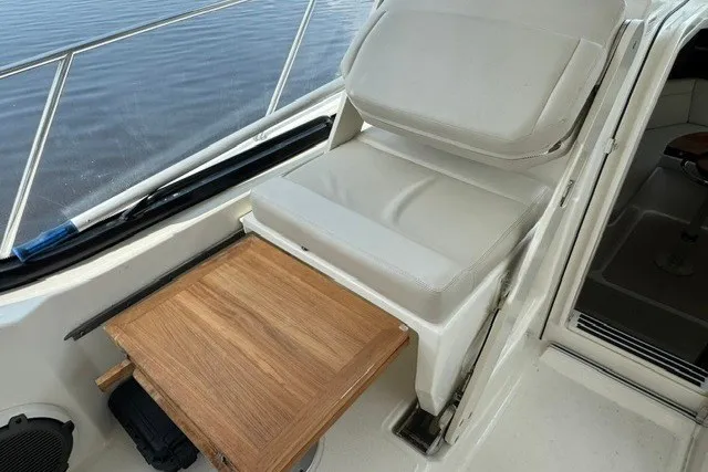 Slide: The Image of 2023 Boston Whaler 325 Conquest interior with cushioned seating and wooden table detail. - 35
