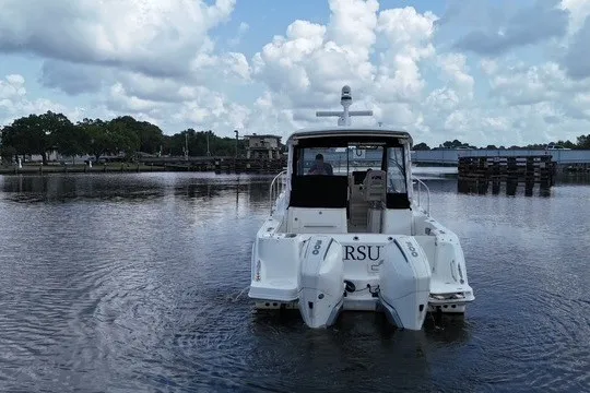 Slide: The Image of 2023 Boston Whaler 325 Conquest boat on calm water under a cloudy sky. - 13