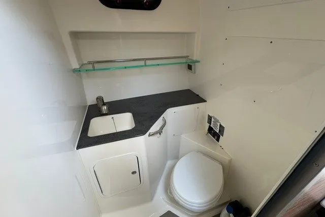 Slide: The Image of 2023 Boston Whaler 325 Conquest boat bathroom with sink, toilet, and storage shelf. - 49