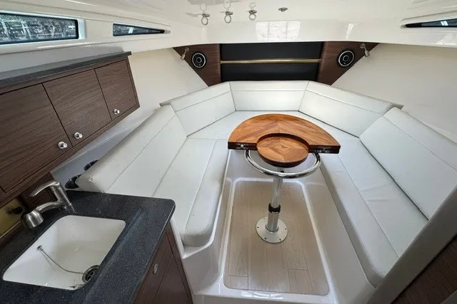 Slide: The Image of 2023 Boston Whaler 325 Conquest cabin interior with seating, table, and kitchenette. - 42