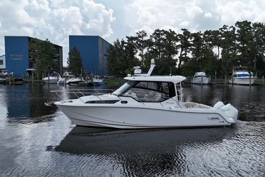The Image of 2023 Boston Whaler 325 Conquest boat on calm water near marina. - 0