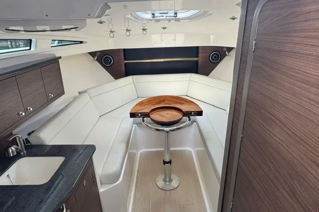 Slide: The Image of 2023 Boston Whaler 325 Conquest cabin interior with modern seating and wooden table. - 40