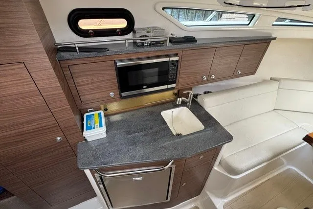 Slide: The Image of 2023 Boston Whaler 325 Conquest interior with kitchenette, microwave, sink, and seating area. - 41