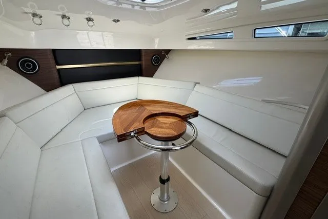 Slide: The Image of Interior of 2023 Boston Whaler 325 Conquest, featuring white seating and a wooden table. - 43