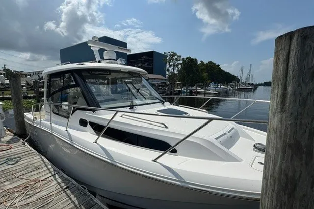 Slide: The Image of 2023 Boston Whaler 325 Conquest docked at a marina under a partly cloudy sky. - 61