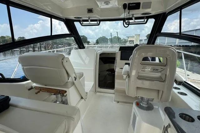 Slide: The Image of 2023 Boston Whaler 325 Conquest interior with helm, seating, and panoramic windows. - 30