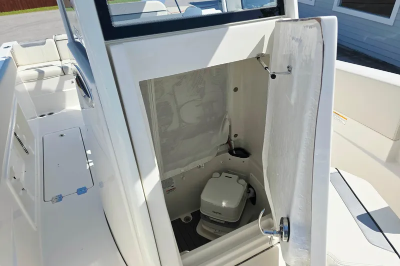 Slide: The Image of The image shows a toilet inside a boat with white walls and a curtain. - 13