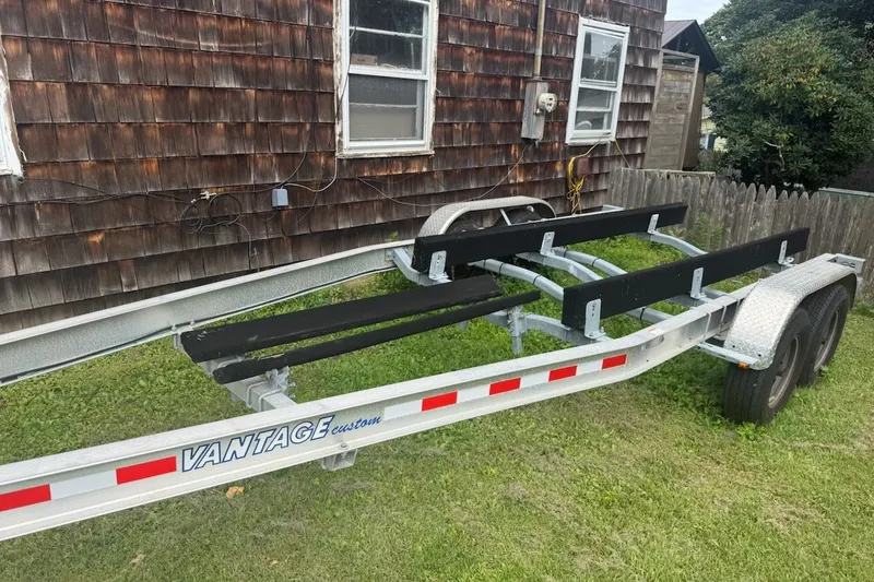 Slide: The Image of Trailer for 2022 Key West 263 FS boat, parked on grass beside wooden house. - 44
