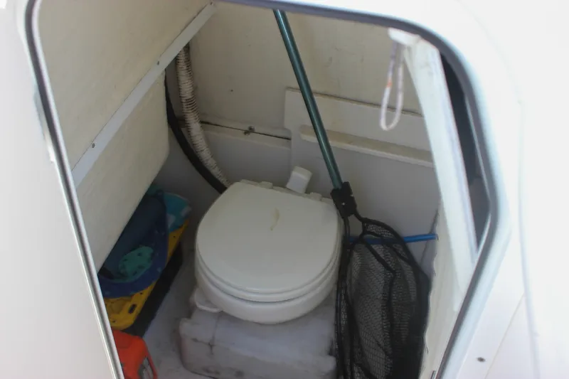 Slide: The Image of Interior of 2022 Key West 263 FS boat featuring compact marine toilet setup. - 24
