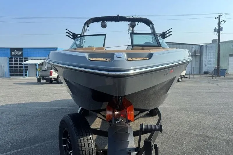 Slide: The Image of 2026 MasterCraft XT23 boat on trailer in industrial parking lot. - 8