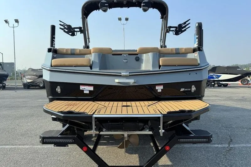 Slide: The Image of 2026 MasterCraft XT23 boat rear view with teak deck and seating in a parking lot. - 4