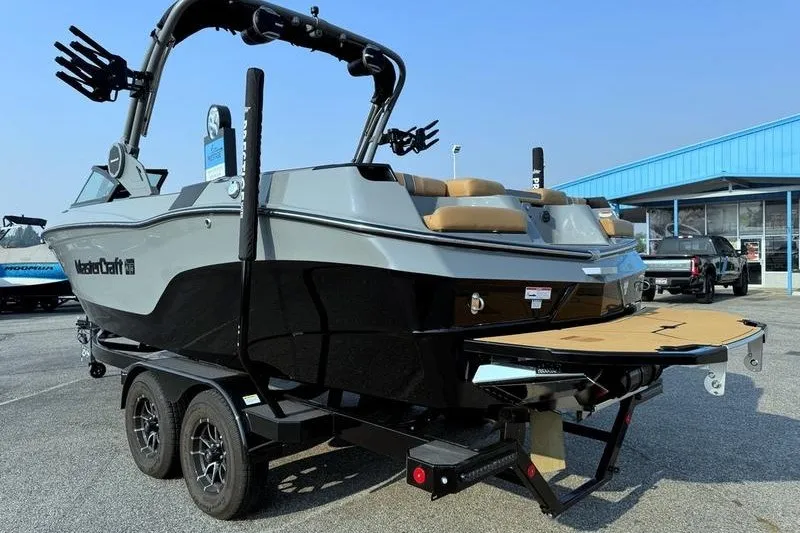 Slide: The Image of 2026 MasterCraft XT23 boat on trailer, displayed outdoors near a blue building. - 6
