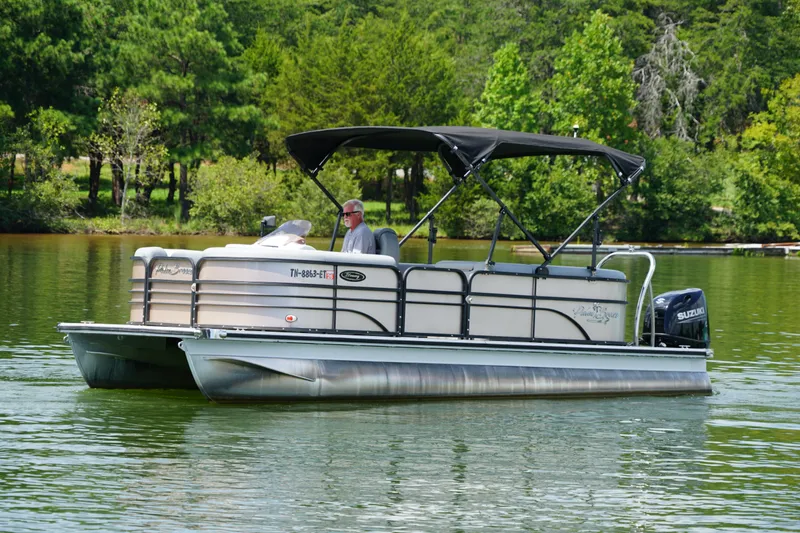 Slide: The Image of 2024 Lexington Palm Breeze Emerg pontoon boat cruising on a serene lake. - 4