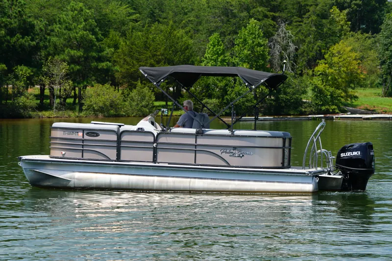 Slide: The Image of 2024 Lexington Palm Breeze Emerg pontoon boat cruising on a serene lake. - 3