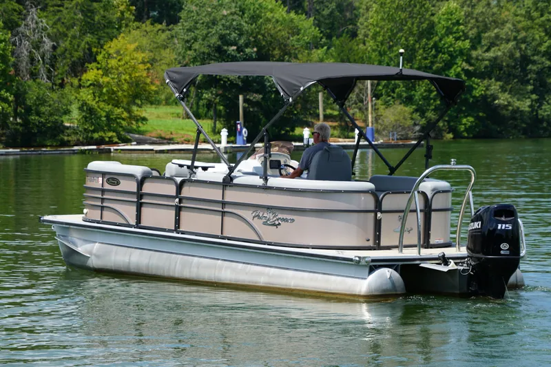 Slide: The Image of 2024 Lexington Palm Breeze Emerg pontoon boat cruising on a serene lake. - 2