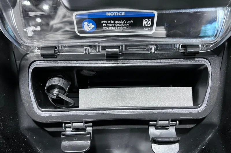 Slide: The Image of 2026 Sea-Doo RXP-X 325 glove box interior with storage compartment and notice label. - 15