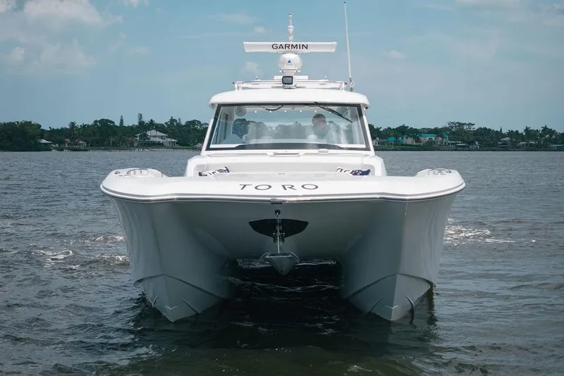 Slide: The Image of 2026 Toro Yachts Toro 42 cruising on a calm waterway under a clear sky. - 6
