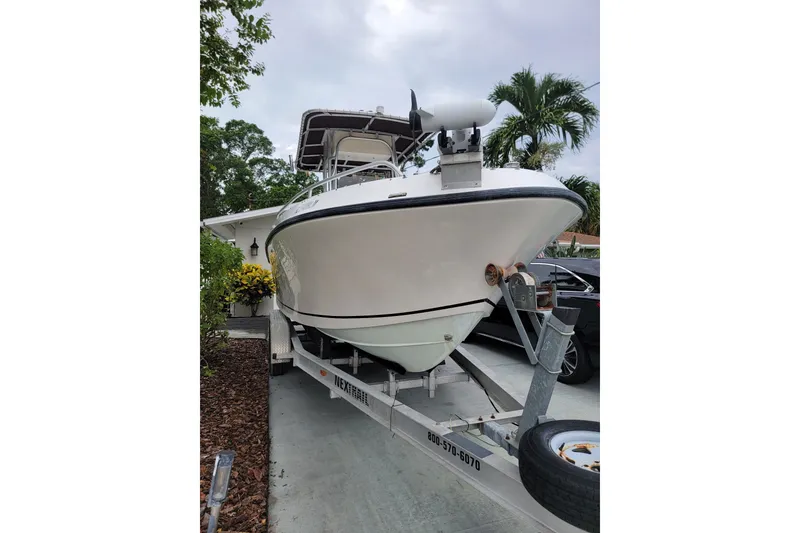 Slide: The Image of 1999 Mako 252 Center Console boat on trailer, parked in driveway with tropical plants. - 13