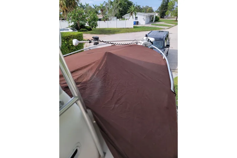 Slide: The Image of 1999 Mako 252 Center Console boat with brown cover, parked in residential area. - 36