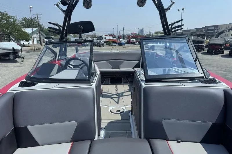 Slide: The Image of 2020 Moomba Max boat interior with gray seating and open windshield, parked outdoors. - 17