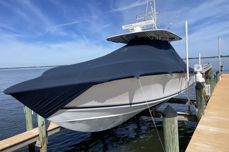 Slide: The Image of 2004 Venture 34 Cuddy boat covered at dock, under clear blue sky. - 11