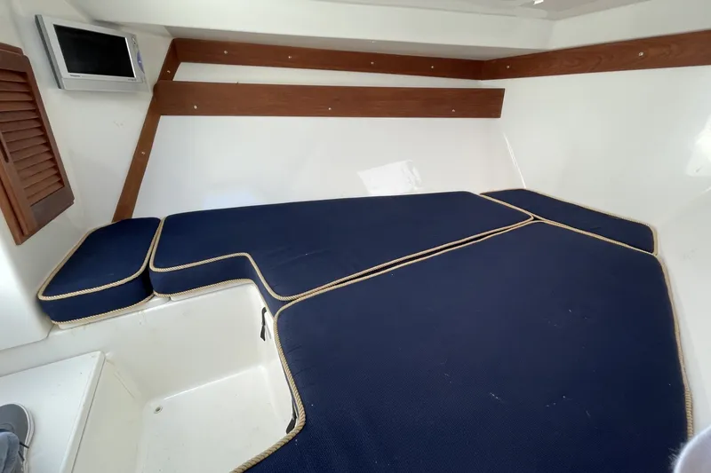 Slide: The Image of Interior cabin of 2004 Venture 34 Cuddy with blue cushions and wooden accents. - 7