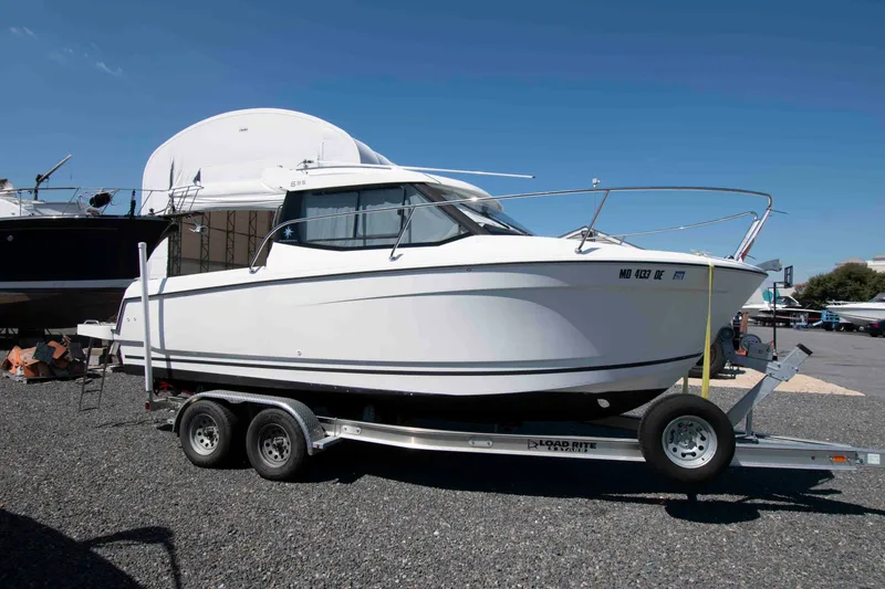 The Image of 2017 Jeanneau Merry Fisher 695 boat on trailer, parked outdoors under clear blue sky. - 0