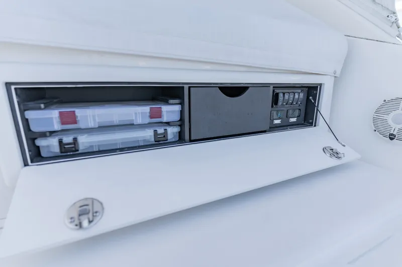Slide: The Image of Storage compartment on 2023 Albemarle 41 Custom Carolina Edition boat, featuring organized tackle boxes and control panel. - 16