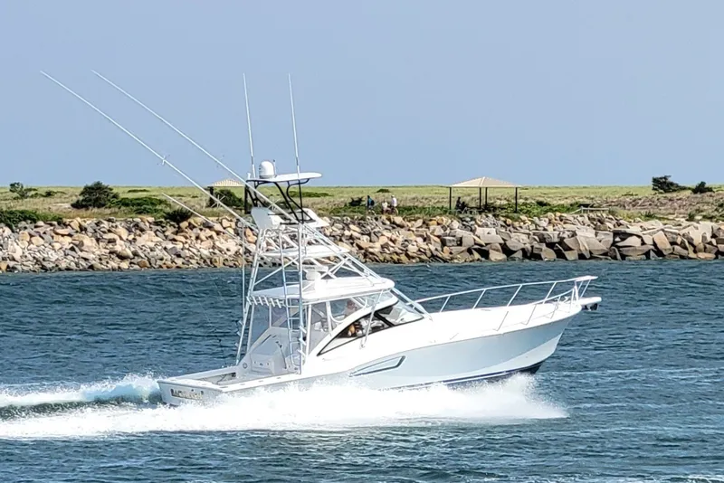 Slide: The Image of 2023 Albemarle 41 Custom Carolina Edition cruising on the water near a rocky shoreline. - 1