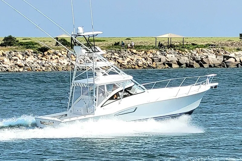 The Image of 2023 Albemarle 41 Custom Carolina Edition cruising on blue water near rocky shoreline. - 0