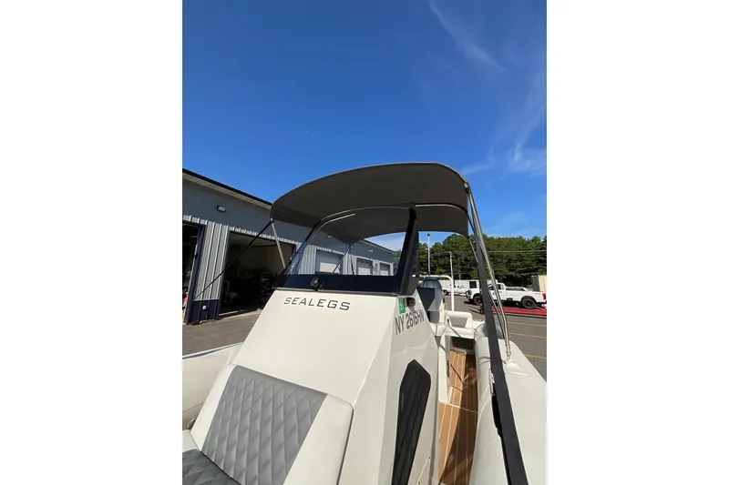 Slide: The Image of 2024 Sealegs 7.5M boat with canopy, parked outdoors under clear blue sky. - 14
