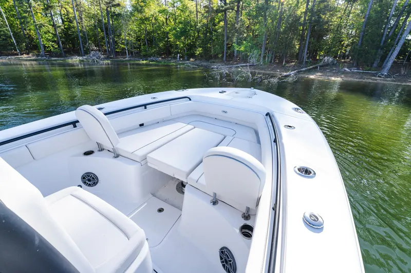 Slide: The Image of 2027 Sea Hunt Ultra 265SE boat with spacious seating, docked near a serene forested shoreline. - 25