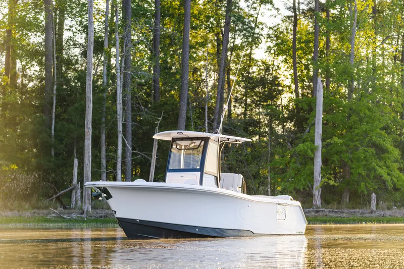 The Image of 2027 Sea Hunt Ultra 265SE boat on calm water, surrounded by lush forest. - 1