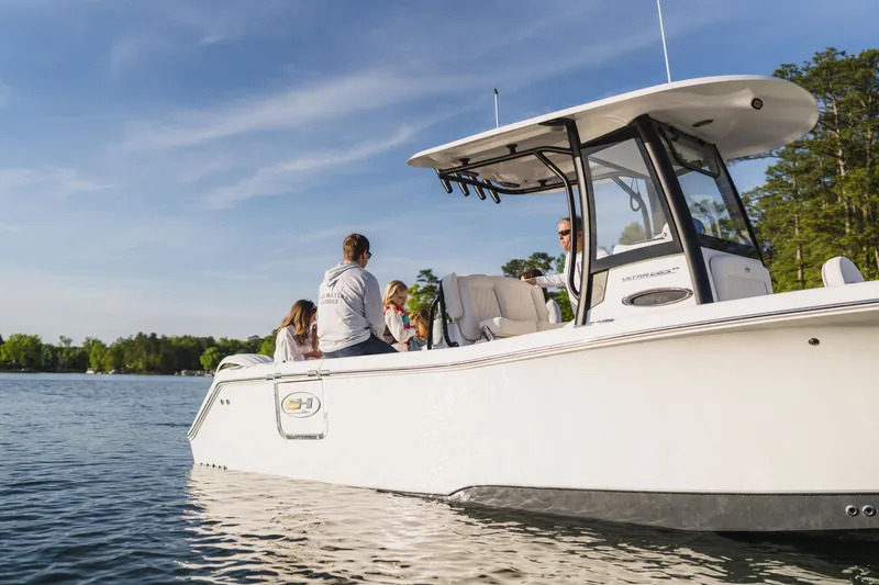 Slide: The Image of 2027 Sea Hunt Ultra 265SE boat on a serene lake with passengers enjoying the ride. - 29