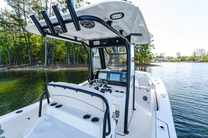 Slide: The Image of 2027 Sea Hunt Ultra 265SE boat on a serene lake with lush forest backdrop. - 21